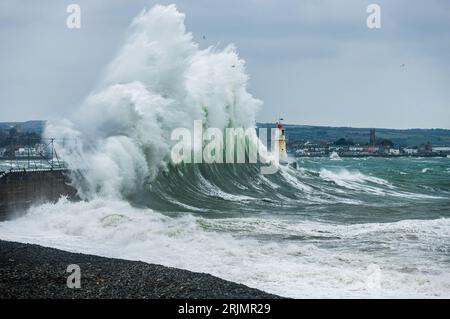 D'énormes vagues s'écrasent dans le port de Newlyn certaines atteignant aussi haut et au-dessus du phare qui se trouve sur le mur du port. Newlyn, Cornwall, Royaume-Uni Banque D'Images