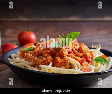 Pâtes spaghetti et sauce tomate avec poulet haché sur fond de bois. Pâtes bolognaises. Banque D'Images