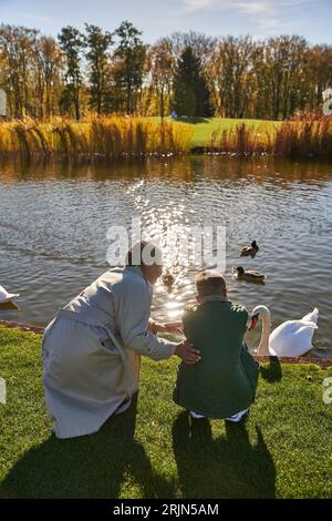 vue arrière de la femme afro-américaine et le garçon regardant le lac avec des canards et des cygnes, l'enfance, la joie Banque D'Images