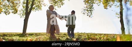 silhouette de la mère et de l'enfant tenant la main dans le parc d'automne, saison d'automne, s'amuser, danser, bannière Banque D'Images