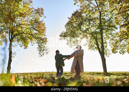 silhouette de la mère et de l'enfant tenant la main dans le parc d'automne, saison d'automne, s'amuser, la liberté, la danse Banque D'Images