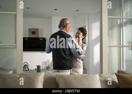 amoureux romantique couple asiatique senior dansant dans le salon à la maison Banque D'Images