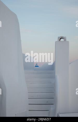 Architecture grecque, escalier blanchi à la chaux avec coucher de soleil caractéristique, escalier blanchi à la chaux de Santorin avec le sommet d'une église grecque en arrière-plan. Banque D'Images