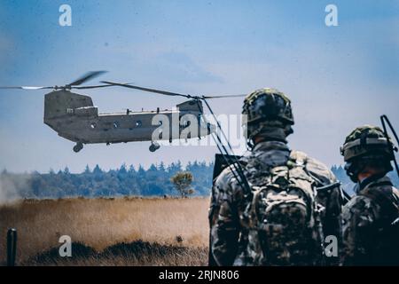 Les deux militaires avec des fusils d'assaut regardant un hélicoptère de l'armée voler Banque D'Images