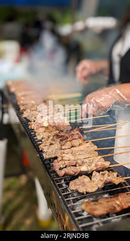 Une personne grillant de la nourriture sur un barbecue au charbon de bois dans un coin salon de restaurant extérieur Banque D'Images