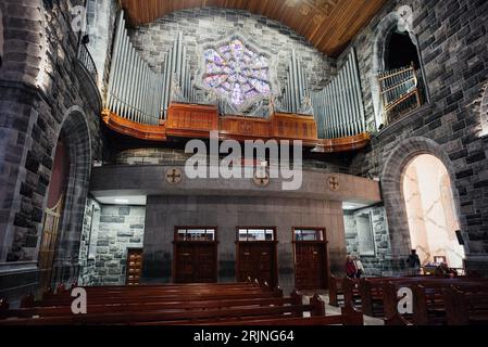Un magnifique intérieur d'église, plein de bancs en bois et un magnifique vitrail Banque D'Images
