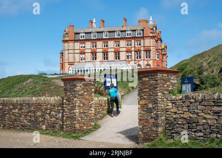 Une femme vacancier portant sa planche de surf et revenant à l'hôtel The Headland à Newquay en Cornouailles en Angleterre au Royaume-Uni. Banque D'Images
