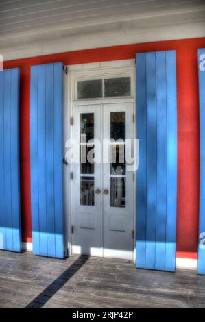 Une vue rapprochée d'une porte avec une fenêtre avec volets blancs sur un bâtiment bleu Banque D'Images