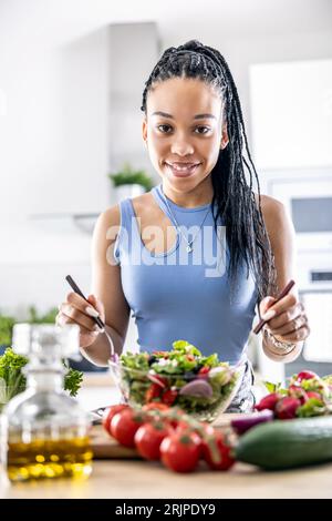 Les mains des femmes mélangent une salade de printemps saine à base de divers ingrédients. Concept de mode de vie sain. Banque D'Images