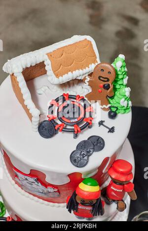 Une image d'un gâteau de Noël festif, avec une maison en pain d'épice en forme et une sélection d'équipements de gym Banque D'Images