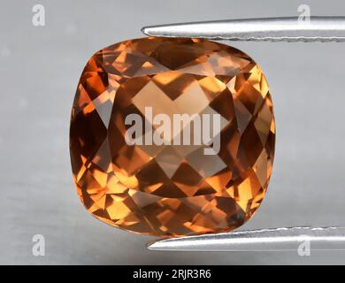 Topaze orange gemme naturelle sur fond gris. Topaze impériale, topaze champagne Banque D'Images