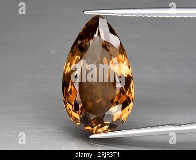 Topaze orange gemme naturelle sur fond gris. Topaze impériale, topaze champagne Banque D'Images