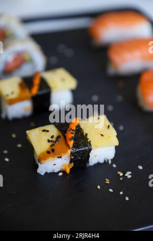 Gros plan d'une assiette noire avec un sushi posé dessus Banque D'Images