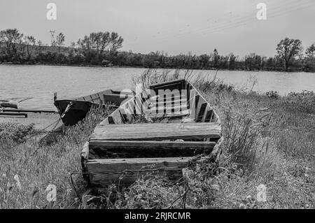 Une échelle de gris d'un bateau en bois sur la rive d'une rivière Banque D'Images