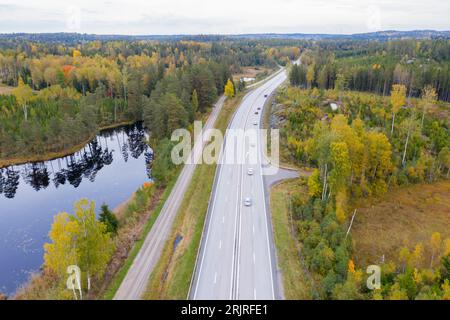 Une route panoramique serpentant à travers une végétation verdoyante, avec des arbres et des arbustes encadrant la route de chaque côté et un lac tranquille au loin Banque D'Images