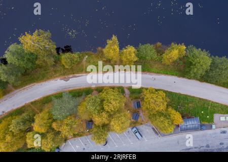 Une route panoramique serpentant à travers une végétation verdoyante, avec des arbres et des arbustes encadrant la route de chaque côté et un lac tranquille au loin Banque D'Images