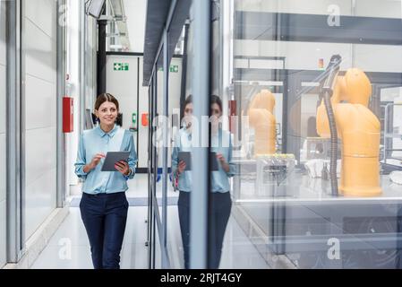 Businesswoman contrôle de robots avec tablette numérique dans la société de haute technologie Banque D'Images