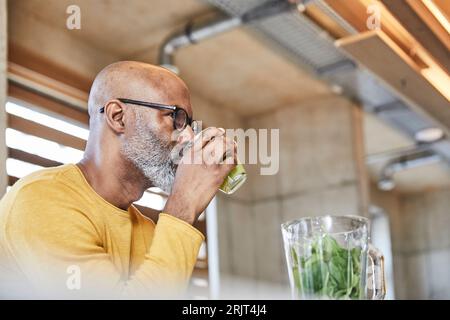 Mature businessman in office de boire un smoothie Banque D'Images
