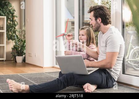 Jeune homme et petite fille jouant avec le modèle d'une éolienne Banque D'Images