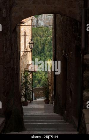 Une arche en pierre menant à un escalier courbe à Pitigliano, Italie Banque D'Images