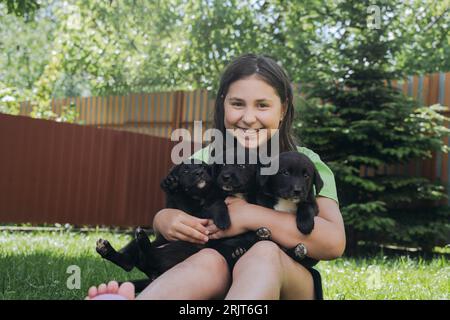 Fille souriante tenant des chiots dans la cour arrière Banque D'Images