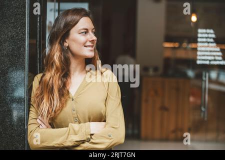 Jeune femme souriante debout les bras croisés Banque D'Images