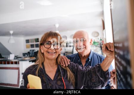 Heureux propriétaire de café debout avec collègue au café Banque D'Images