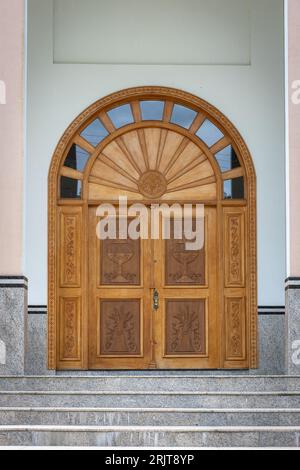 Une vieille porte en bois au design complexe avec un ensemble de marches en béton menant à elle Banque D'Images