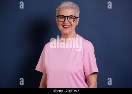 Portrait de femme aînée souriante sur fond bleu Banque D'Images