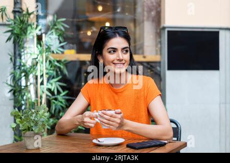 Jeune femme réfléchie appréciant le café assis à table dans le café Banque D'Images