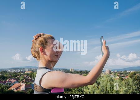 Femme souriante prenant selfie sous le ciel bleu Banque D'Images