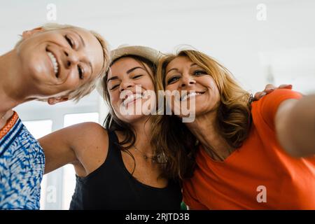 Femme heureuse prenant selfie avec des amis dans l'appartement Banque D'Images