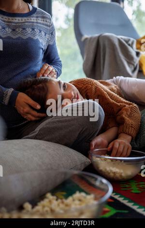 Fille reposant la tête sur les genoux de la mère à la maison Banque D'Images