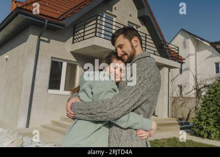 Couple souriant serrant devant la nouvelle maison Banque D'Images