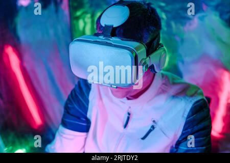 Homme utilisant des simulateurs de réalité virtuelle dans des néons Banque D'Images