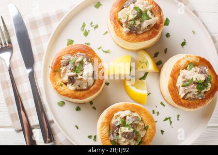 Délicieux vol-au-vent classique farci au poulet, champignons dans une sauce crémeuse en gros plan dans une assiette sur la table. vue de dessus horizontale Banque D'Images