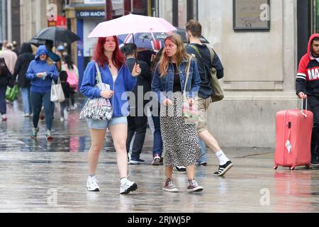 Les femmes s'abritent sous un parapluie par temps humide dans le centre de Londres. Banque D'Images