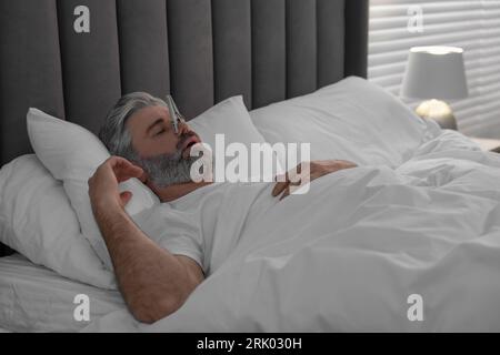 Homme dormant avec des épingles à linge sur son nez dans le lit à la maison. Problème de ronflement Banque D'Images