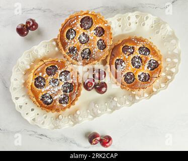 French Flair, Cherry Clafoutis présenté sur White Marble. Tentation alléchante : clafoutis et cerises sur marbre. Banque D'Images