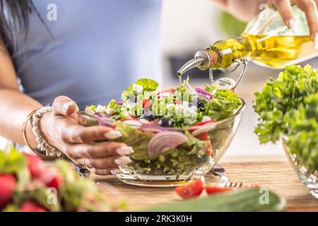 La préparation finale d'une salade saine et à la fin la femme verse de l'huile d'olive. Banque D'Images