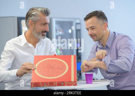 deux hommes d'affaires se préparent à manger de la pizza à emporter Banque D'Images