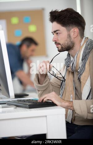 jeune architecte caucasien sérieux assis dans le bureau utilisant l'ordinateur Banque D'Images