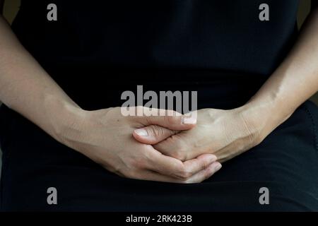 Photo détaillée des mains d'une femme d'âge moyen, mélange d'héritage asiatique et européen, gracieusement croisées. Banque D'Images