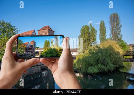 Touriste prenant des photos du vieux pont médiéval sur la rivière Pegnitz à Nuremberg, Allemagne. Le pont du Hangman's Bridge. Banque D'Images