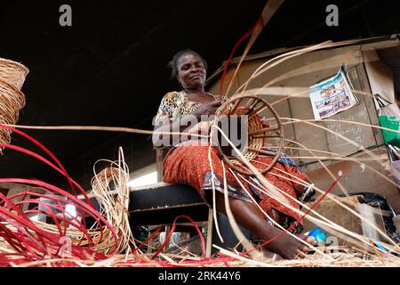 Une femme tisse un panier domestique dans le plus grand « village » de canne à sucre du Nigeria à Mende dans le district du Maryland de Lagos. L'artisanat de canne à sucre au Nigeria, le pays le plus peuplé d'Afrique, prospère au milieu d'un ralentissement économique qui a affecté les petites entreprises et les revenus des gens. Dans le village, des dizaines de personnes, dont des membres de la famille et des chômeurs, sont engagés dans le tissage de différents articles ménagers comme des tables, des paniers, des porte-vin, des pots de fleurs avec du bois de canne provenant de la région marécageuse du delta du Niger. Lagos, Nigeria. Banque D'Images