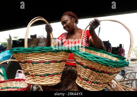 Une femme expose un porte-bagages coloré fait de bois de canne dans le plus grand « village » de canne du Nigeria à Mende dans le district du Maryland à Lagos. L'artisanat de canne à sucre au Nigeria, le pays le plus peuplé d'Afrique, prospère au milieu d'un ralentissement économique qui a affecté les petites entreprises et les revenus des gens. Dans le village, des dizaines de personnes, dont des membres de la famille et des chômeurs, sont engagés dans le tissage de différents articles ménagers comme des tables, des paniers, des porte-vin, des pots de fleurs avec du bois de canne provenant de la région marécageuse du delta du Niger. Lagos, Nigeria. Banque D'Images