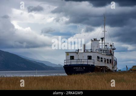 A large vessel sits atop a grassy field, overlooking a tranquil body of water Stock Photo