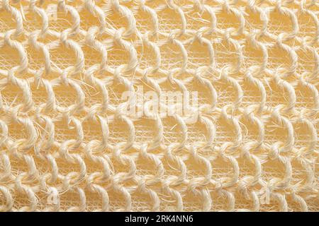 Vue rapprochée de la texture de l'éponge de bain tressée. Texture de couleur pastel beige. Banque D'Images