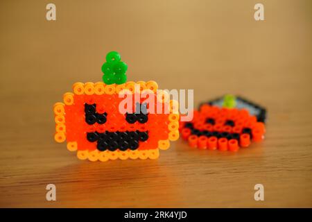 Gros plan de deux breloques perlées en forme de citrouille posées côte à côte sur une surface plane. Banque D'Images