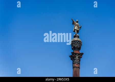 Un monument et une tour de l'horloge se dressent face à un ciel bleu vif : le monument de Colomb à Barcelone Banque D'Images